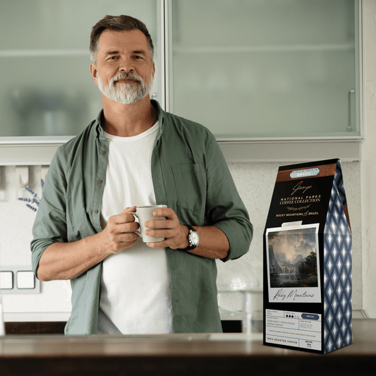 Single-origin specialty coffee from Brazil in collectible GEORGE National Parks Collection packaging by Official Fellow Citizen. Scene of man holding coffee mug in kitchen.