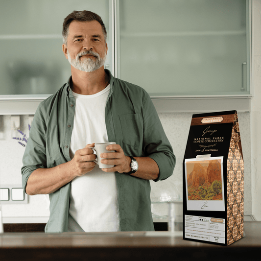 Single-origin specialty coffee from Guatemala in collectible GEORGE National Parks Collection packaging by Official Fellow Citizen. Scene of man holding cup of coffee in kitchen.
